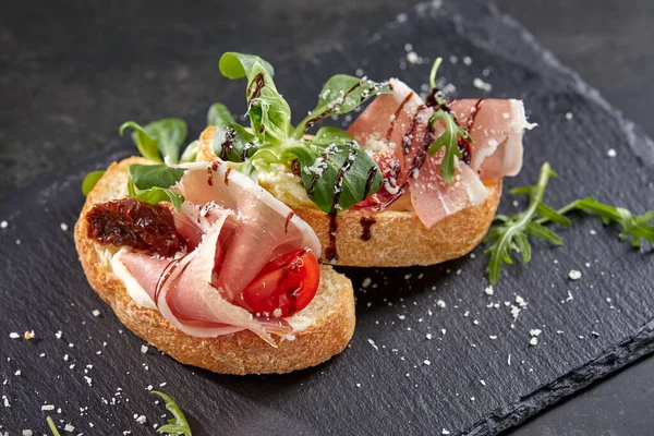 Koyu renkli taş tahtada etli ve sebzeli kanepeler, yakın görüş  