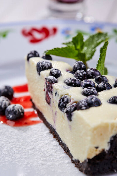 cheesecake with fresh blueberries and mint on white plate, close view 