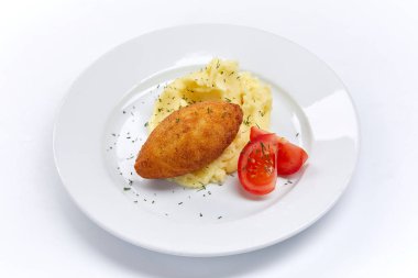Beyaz tabakta patates püresi ve domatesli pirzola, yakın görüş. 