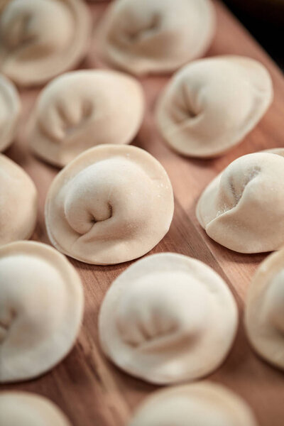 сырые пельмени с творогом на деревянной доске, вид снизу 