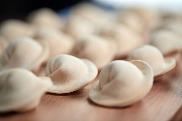 сырые пельмени с творогом на деревянной доске, вид снизу 