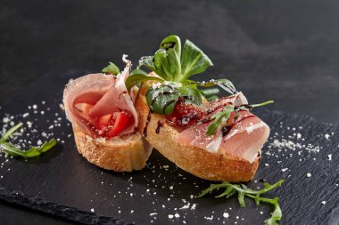 Koyu renkli taş tahtada etli ve sebzeli kanepeler, yakın görüş  