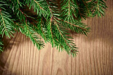 Tahta arka planda Noel ağacı dalları olan bir Noel kartı.