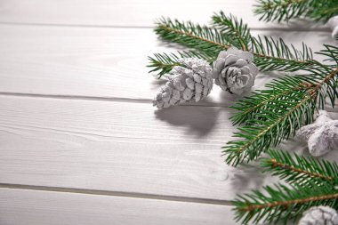 Tahta arka planda Noel ağacı dalları olan bir Noel kartı.