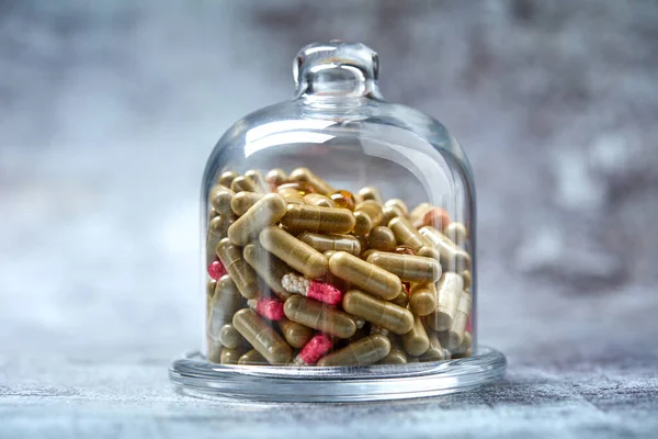 medicine pills and capsules under glass cover on grey surface
