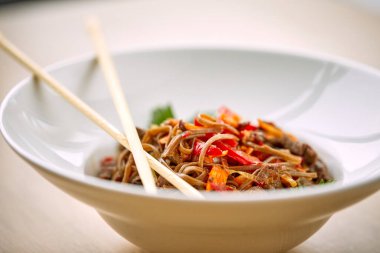 Kızarmış erişteli sobayı beyaz kasede sığır etiyle karıştır, yakın görüş. 