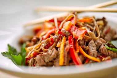 Kızarmış erişteli sobayı beyaz kasede sığır etiyle karıştır, yakın görüş. 