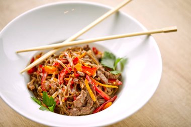 Kızarmış erişteli sobayı beyaz kasede sığır etiyle karıştır, yakın görüş. 