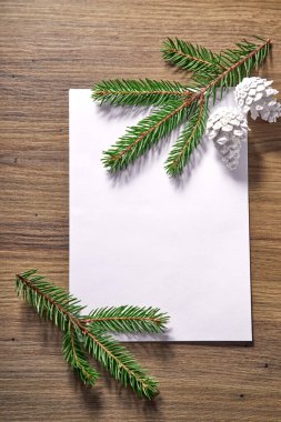 Ahşap arka planda köknar dalları ve konileri olan boş kağıt, Noel konsepti
