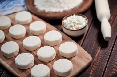 Ahşap kesim tahtasında çiğ süzme peynir krepleri, yakın görüş. 