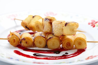 Beyaz tabakta böğürtlen soslu kızarmış tatlı rulo, yakın görüş.