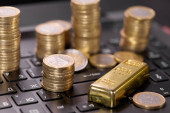 peníze mince se zlatým pruhem na klávesnici notebooku, zblízka 
