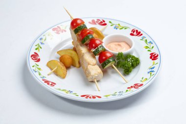 Soslu tavuk kebabı ve beyaz tabakta sebze, yakın görüş.