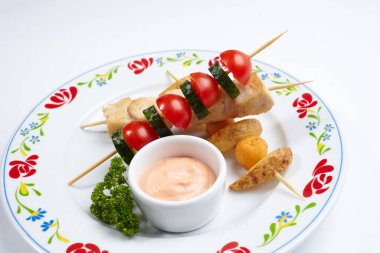 Soslu tavuk kebabı ve beyaz tabakta sebze, yakın görüş.