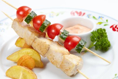 Beyaz tabakta patates ve soslu tavuk kebabı, yakın görüş.