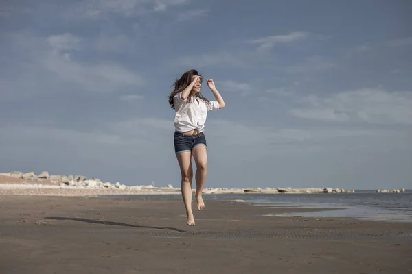 Atrakcyjna dziewczyna skacze po plaży bawiąc się — Zdjęcie stockowe