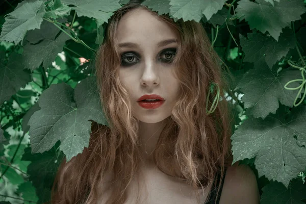 美しいです若いです女性の肖像とともに赤い唇は緑の葉の前に滞在 — ストック写真