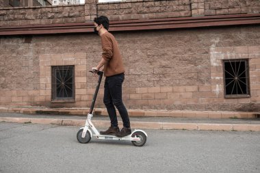 Genç adam şehirde scooter kullanıyor.
