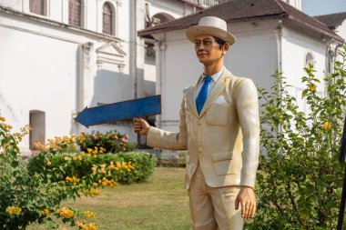 Tam büyümüş bir adamın heykeli elinde yön göstergesi tutuyor.