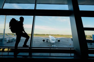 Terminal penceresinin yanında sırt çantalı genç bir adam.