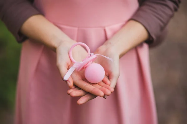 Uma mão de mulher com um boneco bebé. Fundo rosa — Fotografia de Stock