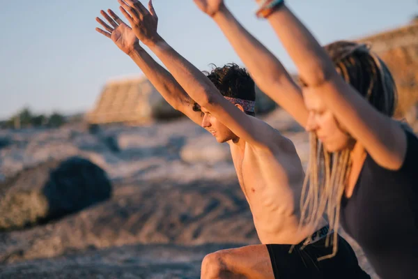 Fitness, sport és életmód koncepció - pár, akik jóga gyakorlatokat csinálnak a strandon — Stock Fotó