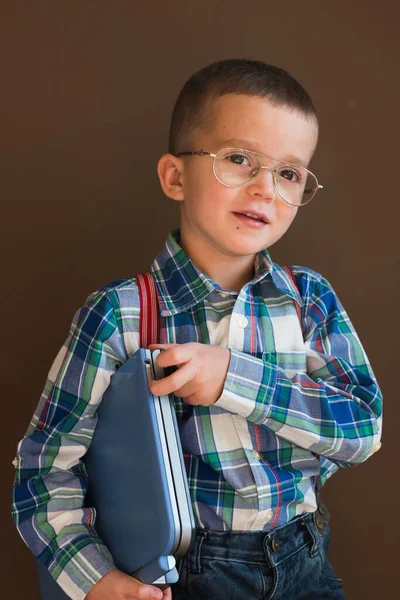 Retrato de un lindo chico serio usando un portátil. Niño en gafas con portátil — Foto de Stock
