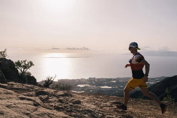 Manan runs cross country on a path in mountain path at Canary Island. Ocean view — Stock Photo, Image