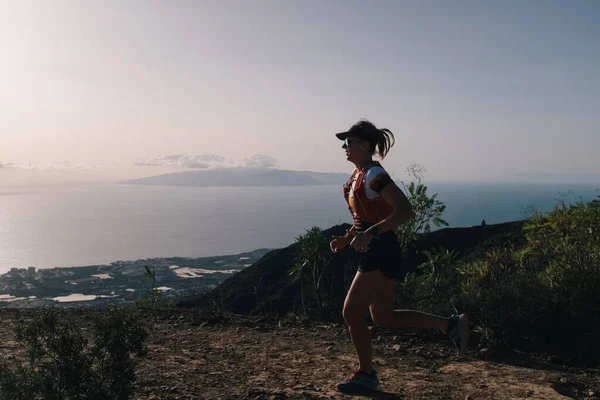 Frau läuft auf einem Pfad im Gebirge auf Kanarische Insel querfeldein. Meerblick Stockbild