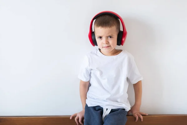 白い背景にヘッドフォンで隔離された白いTシャツの男の子 — ストック写真