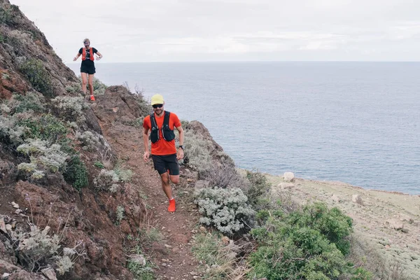 Gruppo di giovani adulti che si allenano e corrono insieme attraverso sentieri in collina all'aria aperta nella natura. — Foto Stock