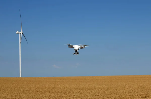 drone flying over wheat field with wind turbine