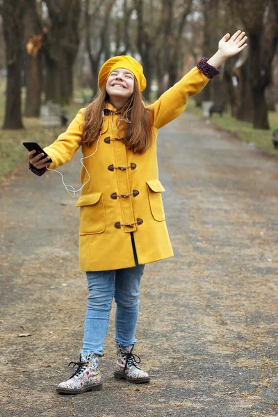 Happy teenage girl listens to music on the smartphone while the — Stock Photo, Image