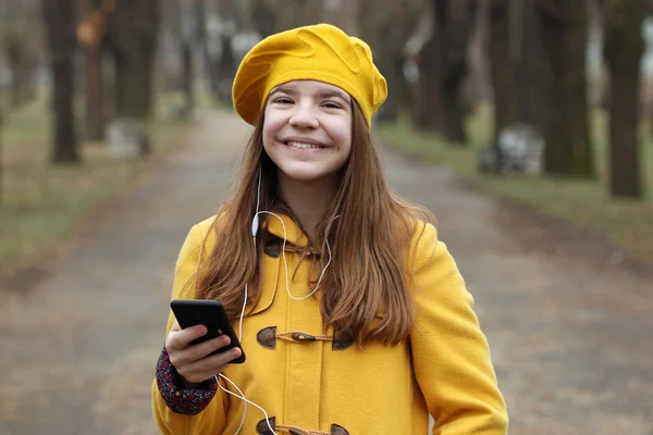 Šťastný dospívající dívka poslouchá hudbu na smartphone — Stock fotografie