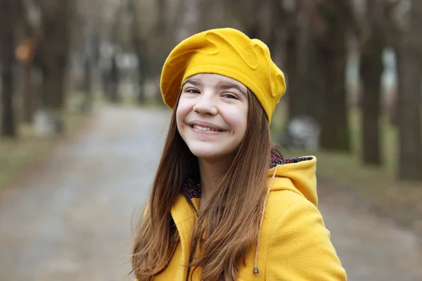 Schöne Teenager-Mädchen in einem gelben Mantel und Baskenmütze Porträt — Stockfoto