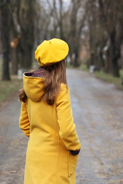 Menina em um casaco amarelo e boina no parque — Fotografia de Stock