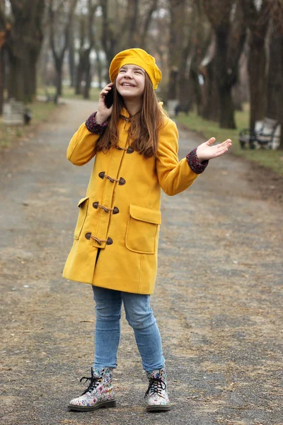 Счастливая девочка-подросток разговаривает по смартфону, пока идет дождь — стоковое фото