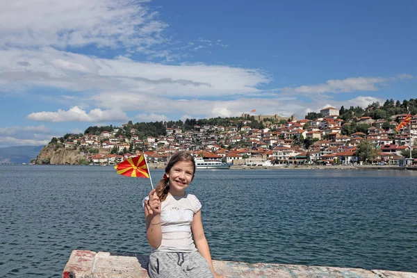 Joyeuse petite fille vagues avec un drapeau macédonien sur le lac Ohrid — Photo