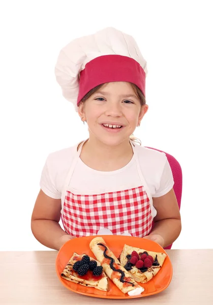 Lycklig liten flicka laga mat med söta crepes på tallrik — Stockfoto