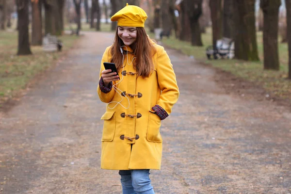 Menina adolescente feliz ouve música no smartphone no parque au — Fotografia de Stock