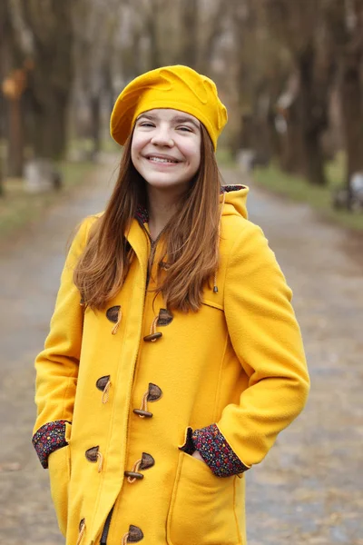 Schöne Teenager-Mädchen in einem gelben Mantel und Baskenmütze Porträt — Stockfoto