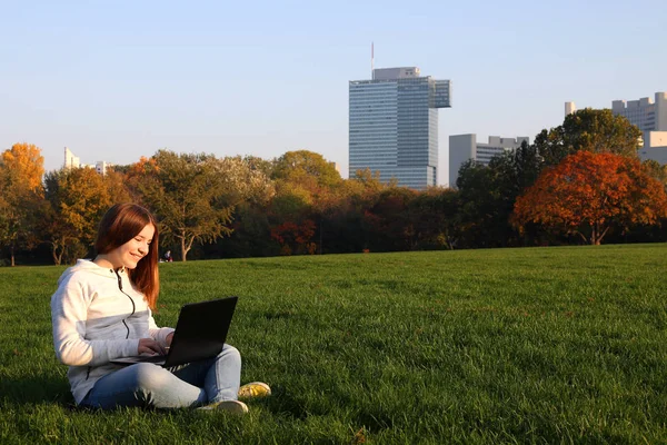 Gelukkig tiener meisje typen op laptop in park — Stockfoto