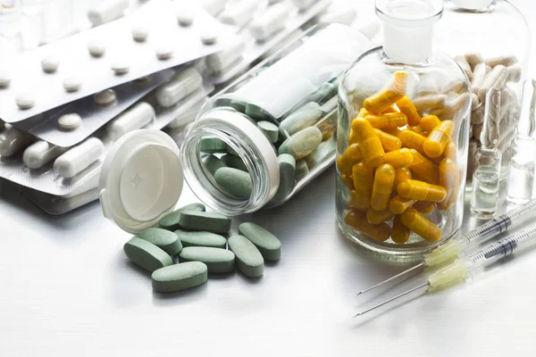 Medicines in tablets, capsules and injections on a metal table as a symbol of the pharmaceutical industry