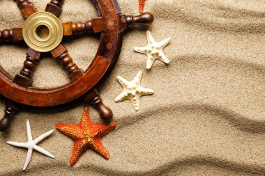 Geminin direksiyon simidi ve plaj kum üzerinde çeşitli deniz yıldızı