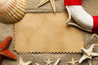 Çeşitli kabukları ve deniz yıldızı, kırmızı ve beyaz lifebuoy ve boş kağıt sayfası sahilde