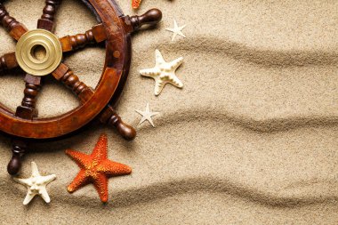 Geminin direksiyon simidi ve kum zemin üzerine çeşitli deniz yıldızı