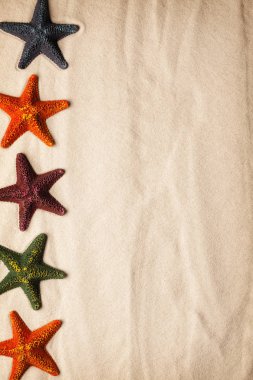 Plaj arka plan - plaj kum üzerinde beş renkli deniz yıldızı