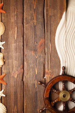 Geminin direksiyon simidi, sahil kumu ve kabukları bir denizci olarak semboller ve benzetmeler