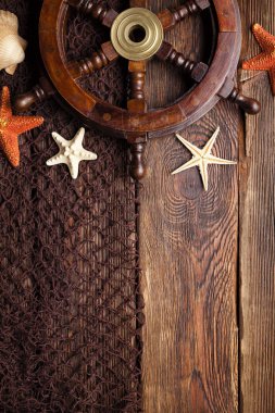 Geminin direksiyon simidi, deniz yıldızı ve balık ağı üzerinde ahşap masa