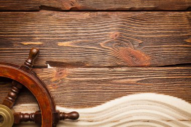 Geminin direksiyon simidi ve ahşap plakalar arka plan üzerinde kum plaj